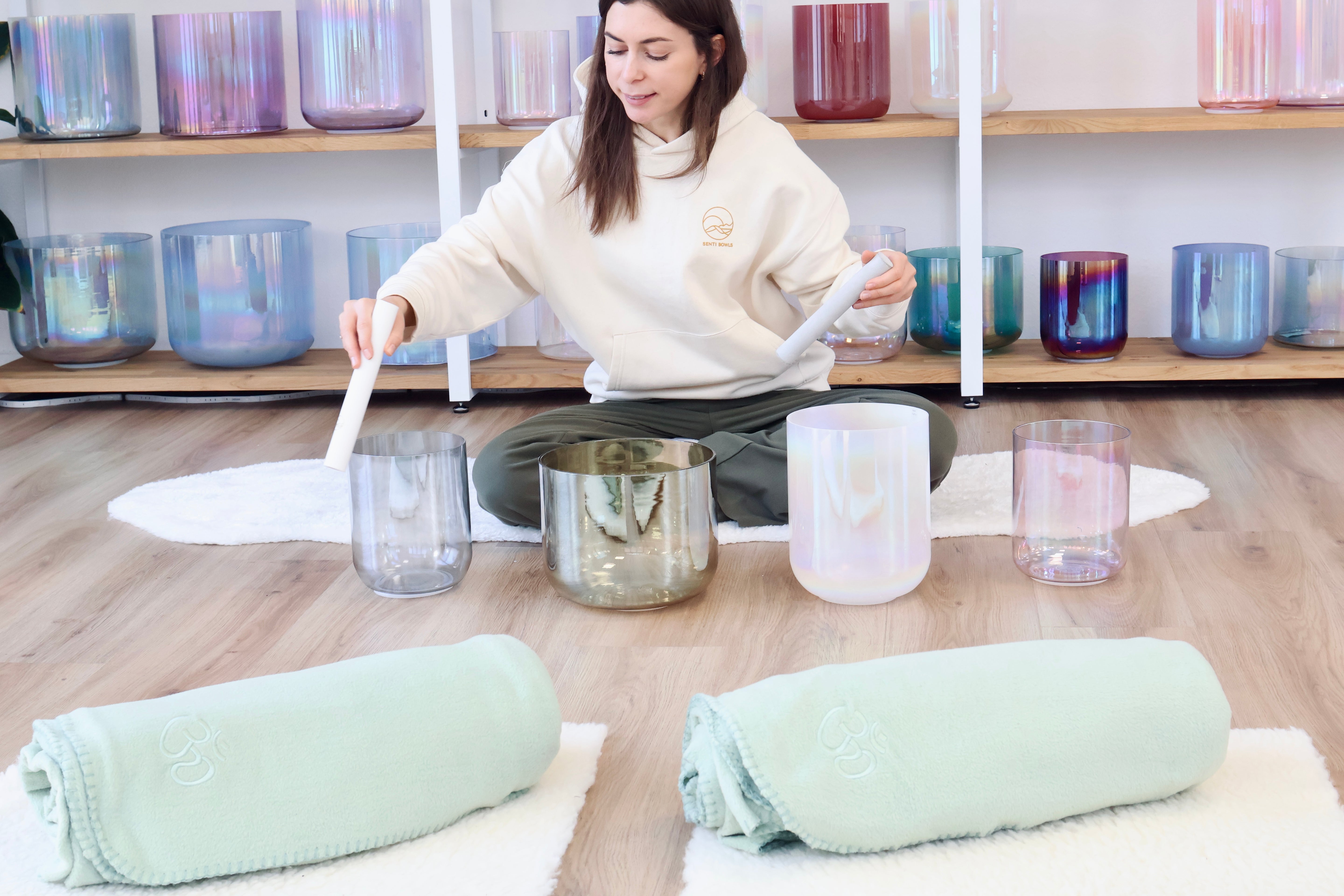 Lea, Gründerin von Senti, spielt eine Senti Bowls Kristallklangschale aus Quarzkristall in einem modernen Studio.